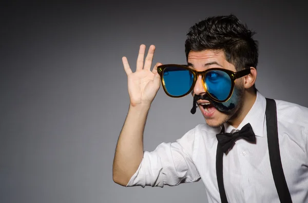 Jonge Kaukasische man dragen van een zonnebril tegen grijs — Stockfoto