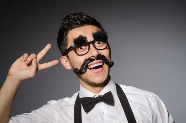 Junger Mann mit falschem Schnurrbart isoliert auf grau — Stockfoto