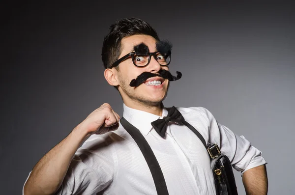 Homem caucasiano jovem com bigode falso contra cinza — Fotografia de Stock