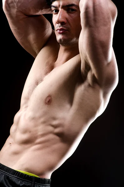 Hombre musculoso posando en estudio oscuro —  Fotos de Stock