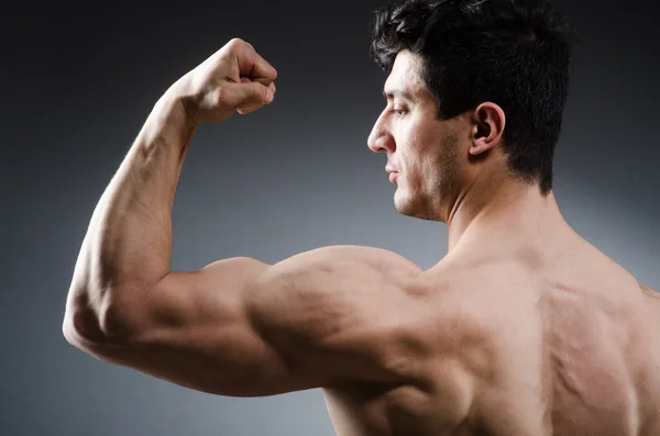 Hombre musculoso posando en estudio oscuro — Foto de Stock