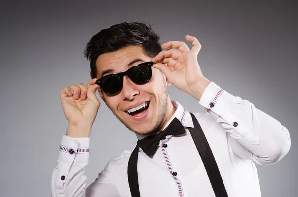 Hombre sonriente en gafas de sol contra gris — Foto de Stock