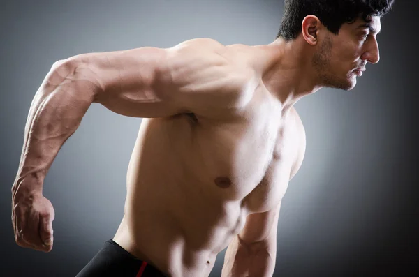 Hombre musculoso posando en estudio oscuro — Foto de Stock