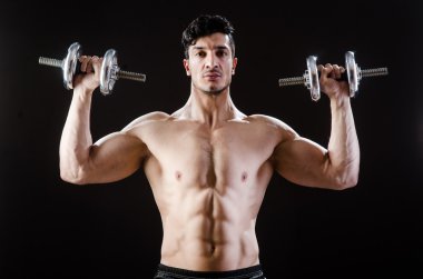 Kaslı adam karanlık stüdyoda poz veriyor.