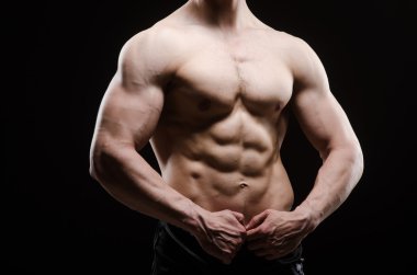 Kaslı adam karanlık stüdyoda poz veriyor.