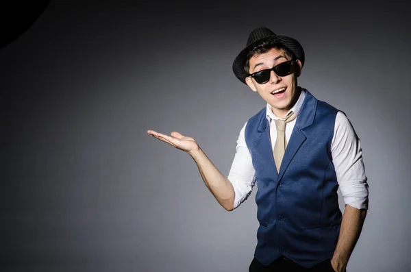 Hombre joven en chaleco azul y sombrero contra gris — Foto de Stock