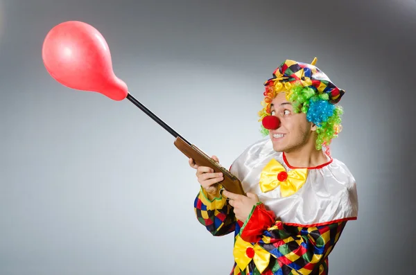 Payaso con globo y rifle en concepto divertido — Foto de Stock