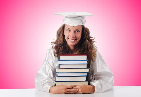 Happy graduate with lots of books on white — Stock Photo, Image