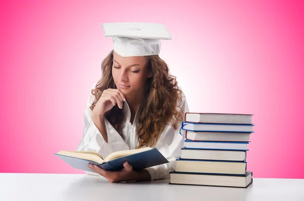 Happy graduate with lots of books on white — Stock Photo, Image