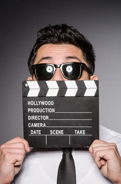 Jovem caucasiano homem com clapperboard contra cinza — Fotografia de Stock