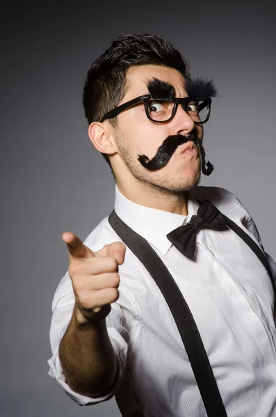 Homem caucasiano jovem com bigode falso contra cinza — Fotografia de Stock