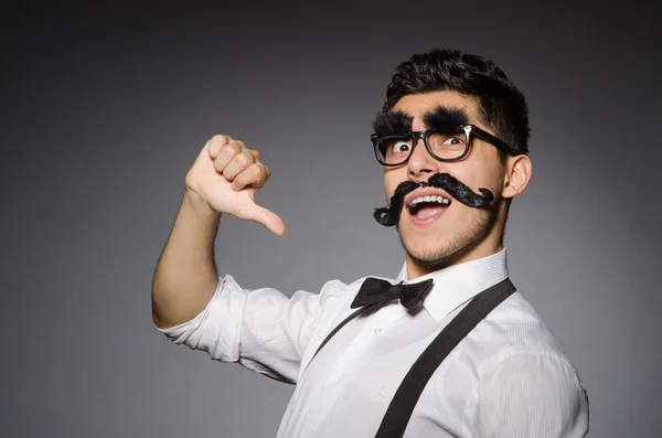 Homem caucasiano jovem com bigode falso contra cinza — Fotografia de Stock