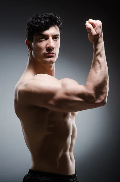 Hombre musculoso posando en estudio oscuro —  Fotos de Stock