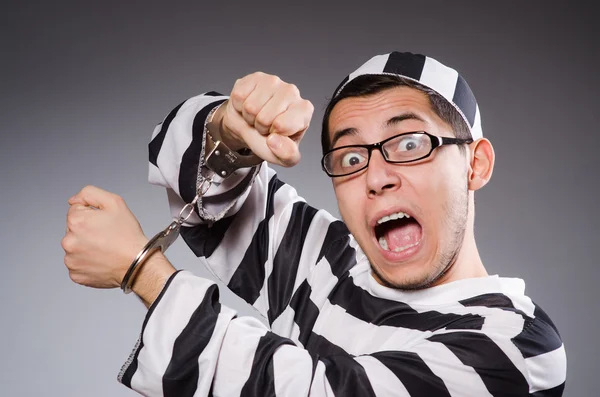 Young prisoner in handcuffs against gray — Stock Photo, Image