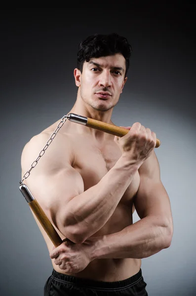 Muskulös stark man med nunchucks — Stockfoto