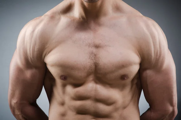 Muscular man posing in dark studio — Stock Photo, Image