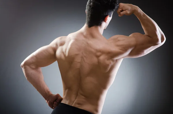 Muscular man posing in dark studio — Stock Photo, Image