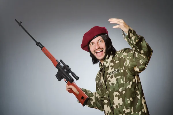 Voják s zbraň proti šedi — Stock fotografie