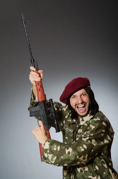 Soldado com pistola contra cinza — Fotografia de Stock