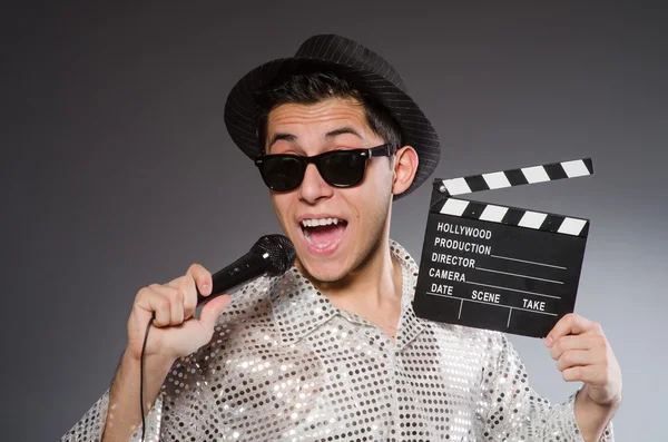 Jovem homem alegre com clapperboard e microfone — Fotografia de Stock