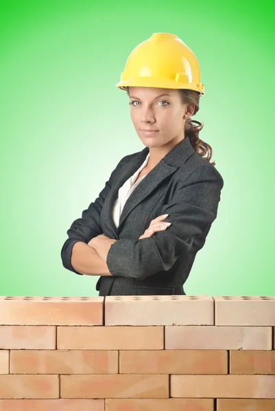 Jovem construtor feminino perto da parede de tijolo — Fotografia de Stock