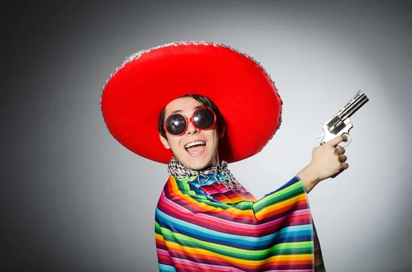 Uomo in vivido poncho messicano con pistola contro il grigio — Foto Stock