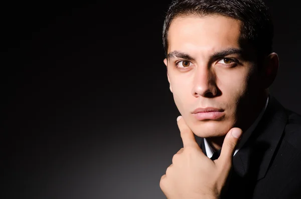 Young businessman in dark studio — Stock Photo, Image