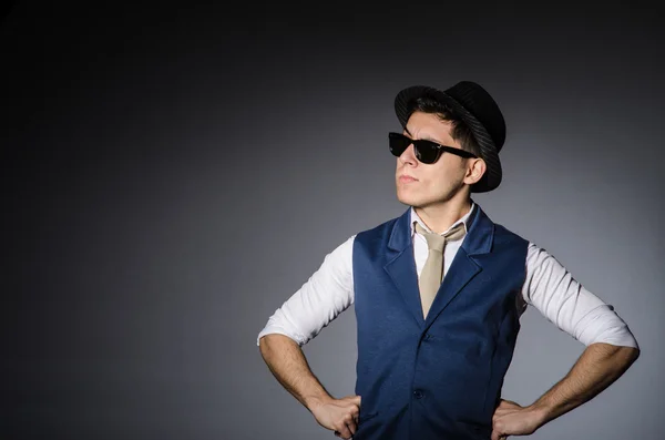 Hombre joven en chaleco azul y sombrero contra gris — Foto de Stock