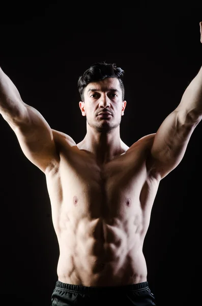 Muscular man posing in dark studio — Stock Photo, Image