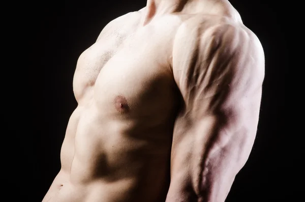 어두운 스튜디오에서 포즈를 취하는 근육질의 남자 — 스톡 사진