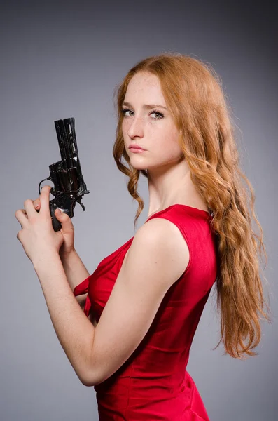 Mädchen im roten Kleid mit Handfeuerwaffe gegen Grau — Stockfoto
