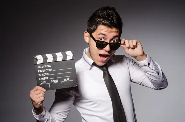 Jovem caucasiano homem com clapperboard contra cinza — Fotografia de Stock