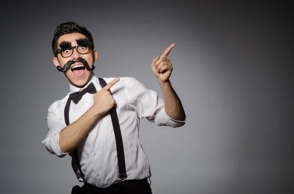 Homem caucasiano jovem com bigode falso contra cinza — Fotografia de Stock