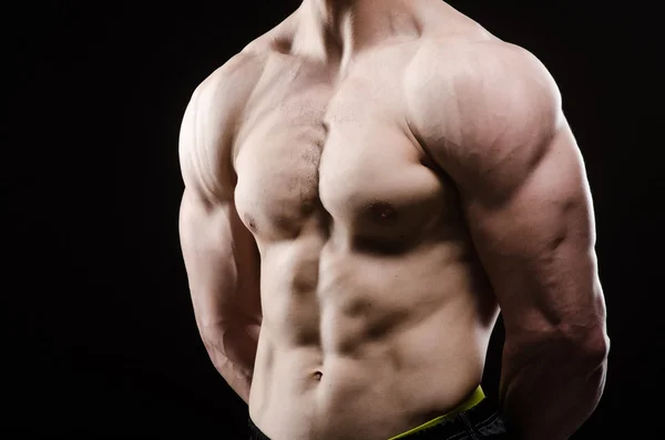 Muscular man posing in dark studio — Stock Photo, Image