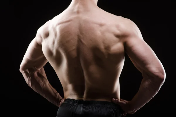 Muscular man posing in dark studio — Stock Photo, Image