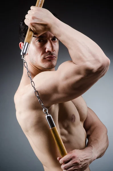 Muscular strong man with nunchucks — Stock Photo, Image