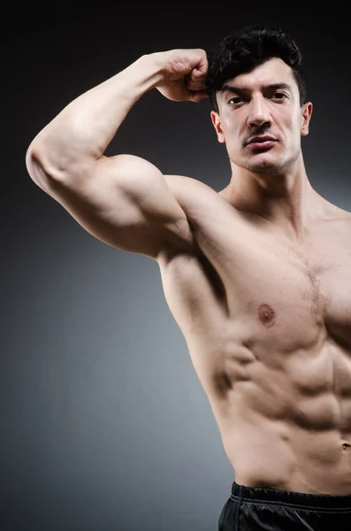 Muscular man posing in dark studio — Stock Photo, Image