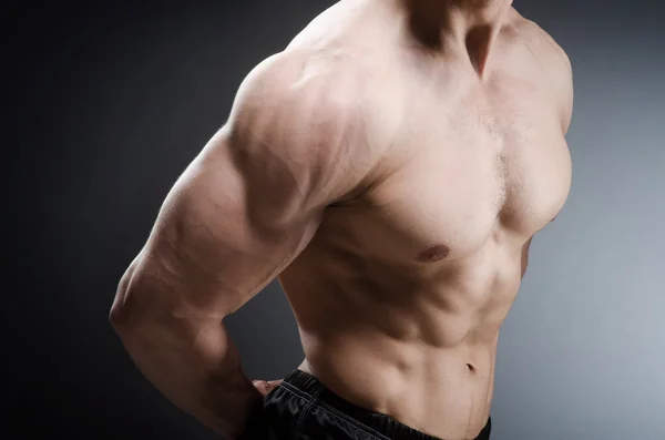 Hombre musculoso posando en estudio oscuro — Foto de Stock