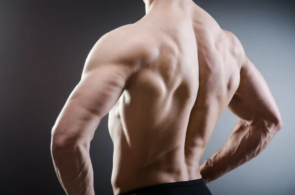 Muscular man posing in dark studio — Stock Photo, Image