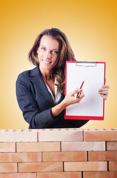 Mujer constructora y pared de ladrillo — Foto de Stock