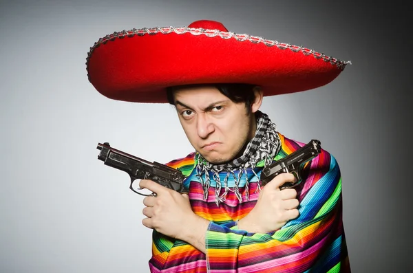 Man in vivid mexican poncho holding handgun against gray — Stock Photo, Image