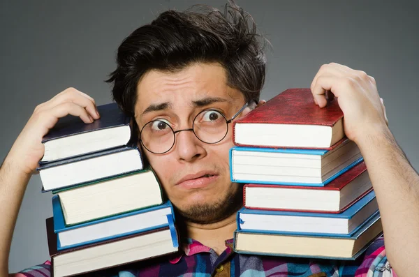 Estudante engraçado com muitos livros — Fotografia de Stock