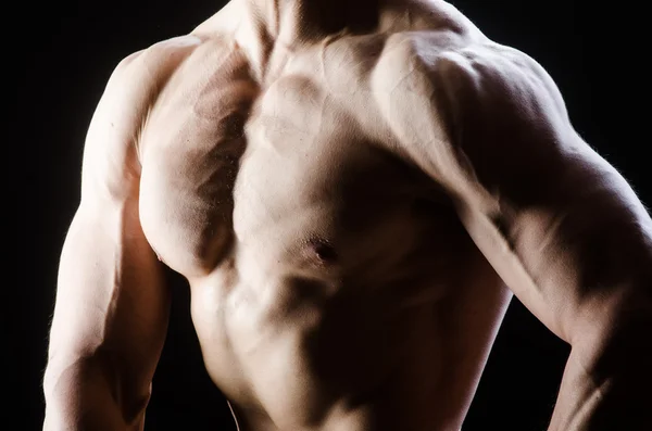 Muscular man posing in dark studio — Stock Photo, Image