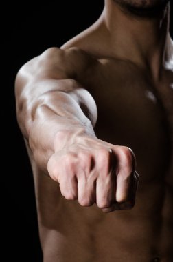 Kaslı adam karanlık stüdyoda poz veriyor.