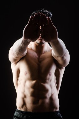 Kaslı adam karanlık stüdyoda poz veriyor.