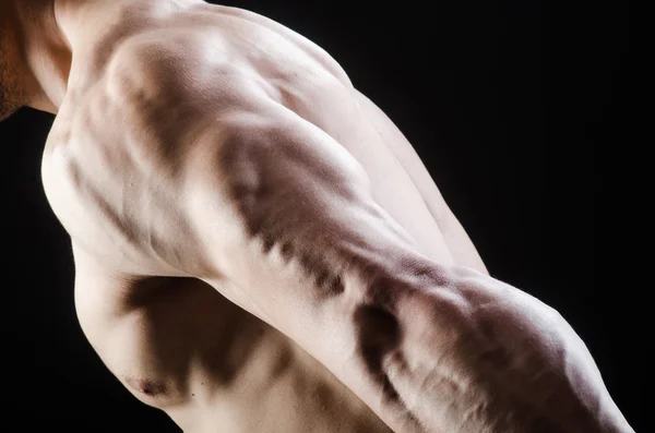 Muscular man posing in dark studio — Stock Photo, Image