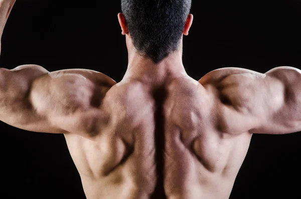 Muscular man posing in dark studio — Stock Photo, Image