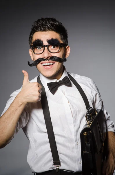 Homem caucasiano jovem com bigode falso contra cinza — Fotografia de Stock