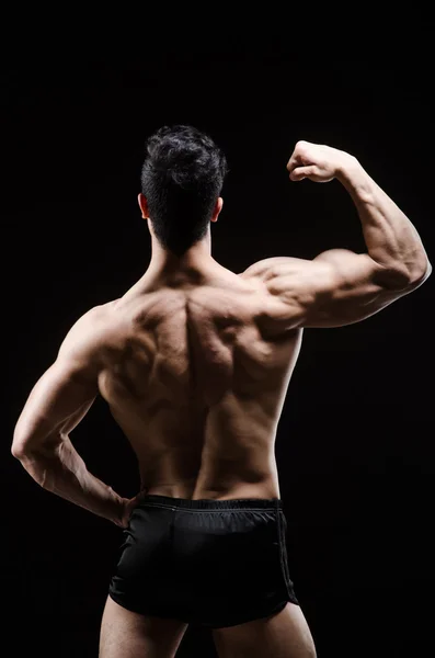 Hombre musculoso posando en estudio oscuro — Foto de Stock