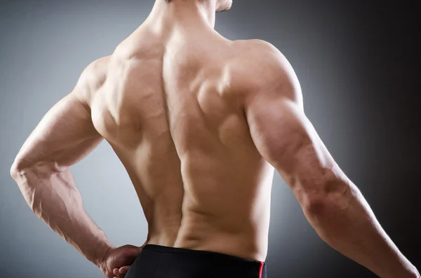 Muscular man posing in dark studio — Stock Photo, Image